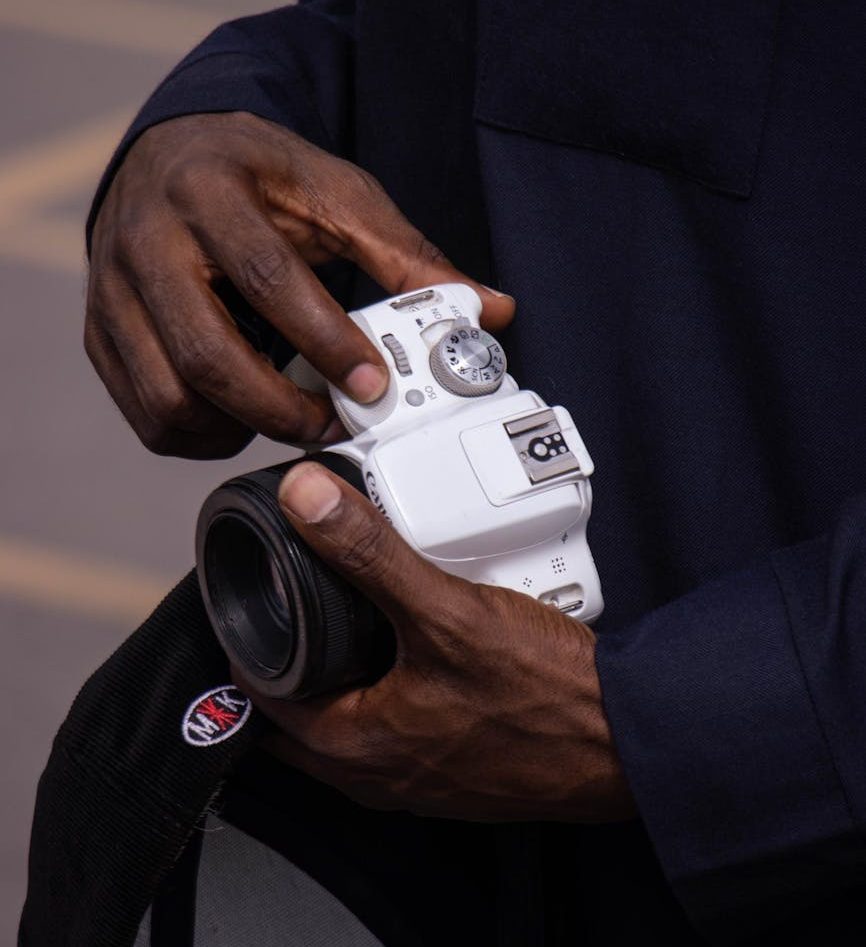 A man is holding a silver camera in his hands. 